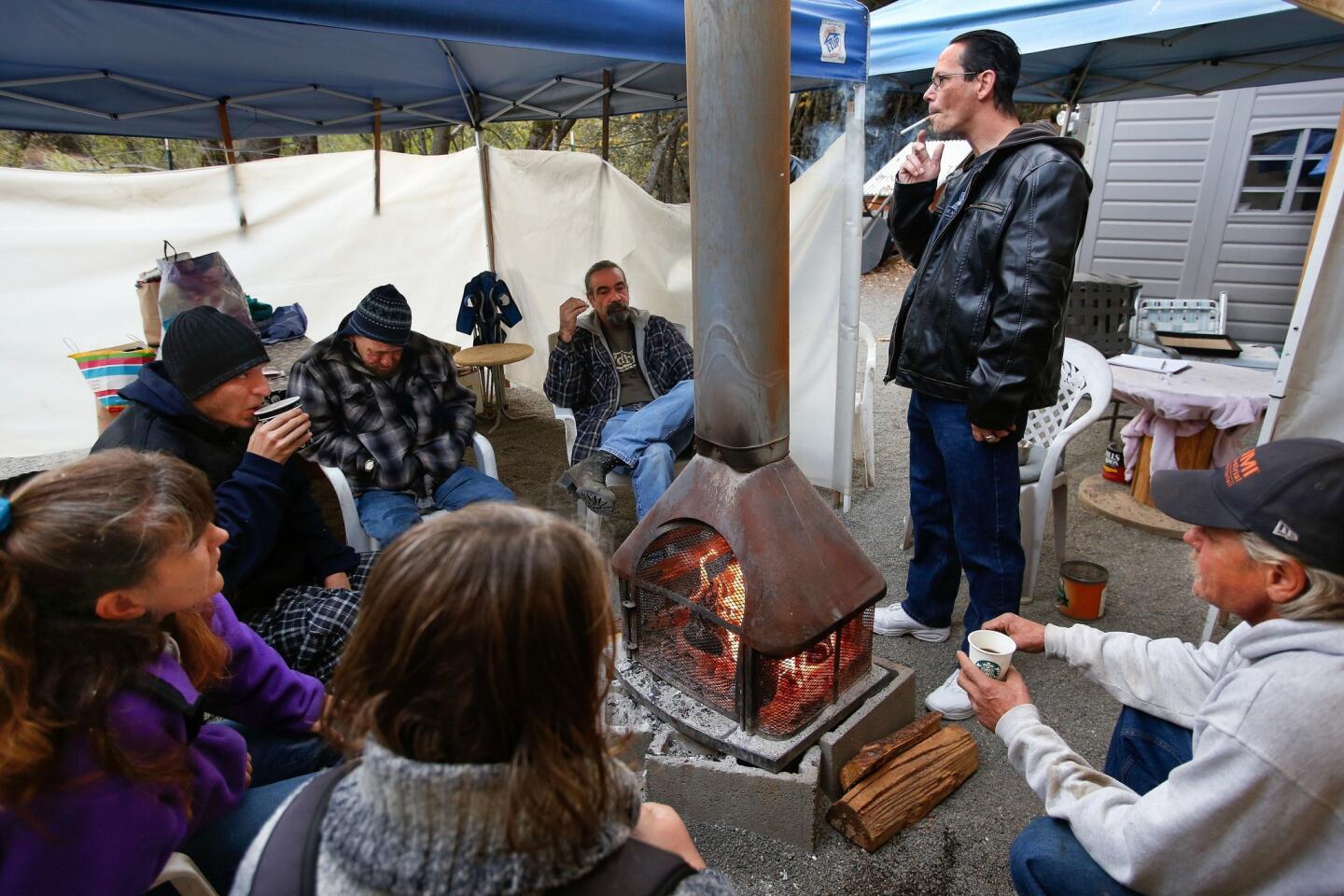 Kenneth Green (standing), the president of the community council at Hangtown Haven, warms himself by the fire with other residents in the early morning.