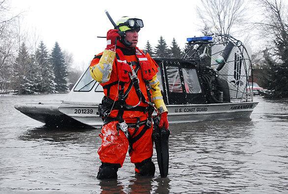 Coast Guard Petty Officer 3rd Class Christopher Wheeler radios his helicopter crew during a search and rescue mission in Fargo. The Coast Guard and state and local agencies are coordinating rescue efforts in flood-prone communities in Fargo, Oxbow and Bismarck.