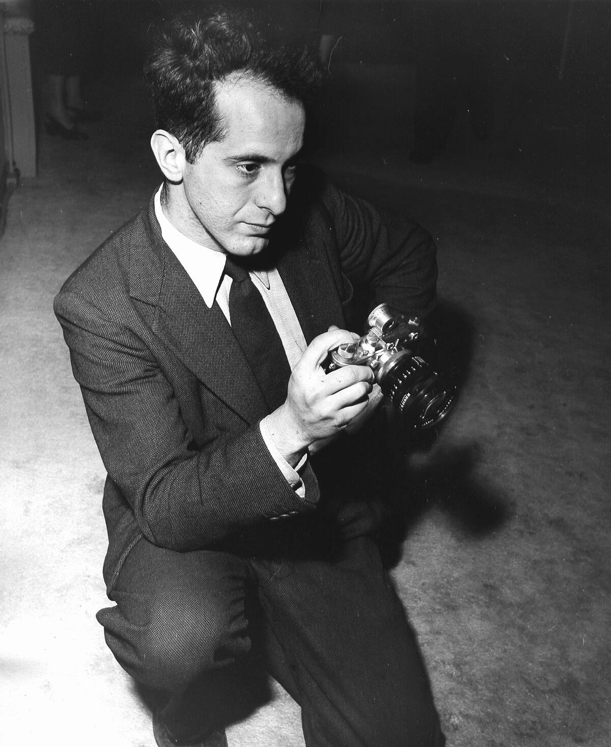 American photographer Robert Frank holding a prewar Leica camera, 1954.