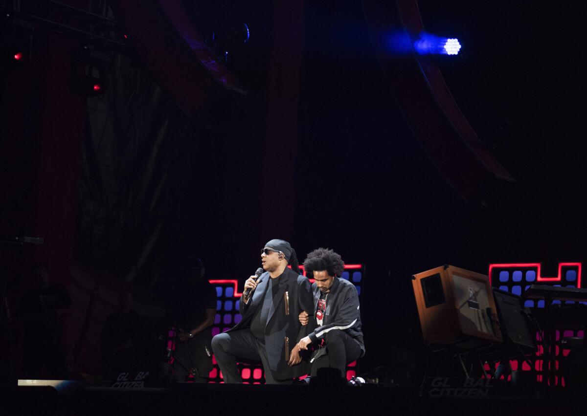 Stevie Wonder, left, takes a knee "for the country" with his son, Kwame Morris, before performing at the 2017 Global Citizen Festival in New York's Central Park on Sept. 23.