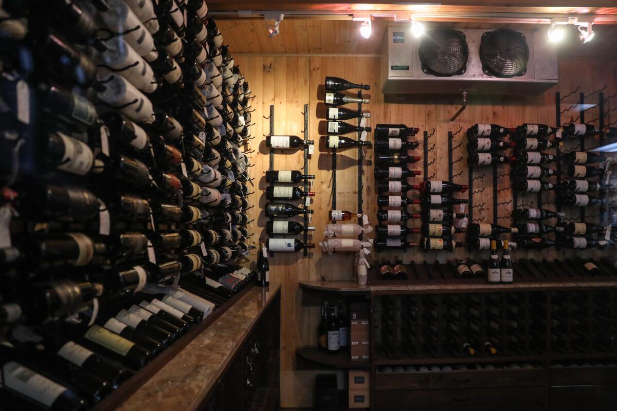 Bottles of wine fill racks lining the walls of a wood-paneled room