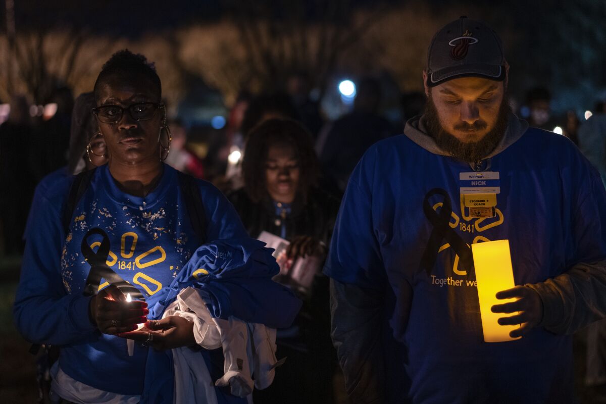 Walmart employees stand together during a candlelight vigil at Chesapeake City Park in Chesapeake, Va., Monday, Nov. 28, 2022, for the six people killed at a Walmart in Chesapeake, Va., when a manager opened fire with a handgun before an employee meeting last week. (AP Photo/Carolyn Kaster)