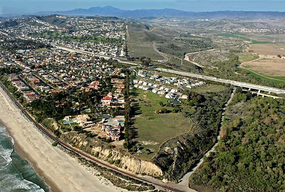 In this aerial view looking north, the city of San Clemente is at the left and San Onofre State Beach is at the right, with Interstate 5 running parallel to the coastline. The proposed six-lane Foothill South toll road would go through the state beach territory, roughly straddling its border.
