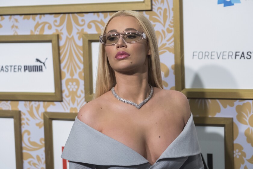 A woman with blond hair wearing tinted glasses and an off-shoulder dress