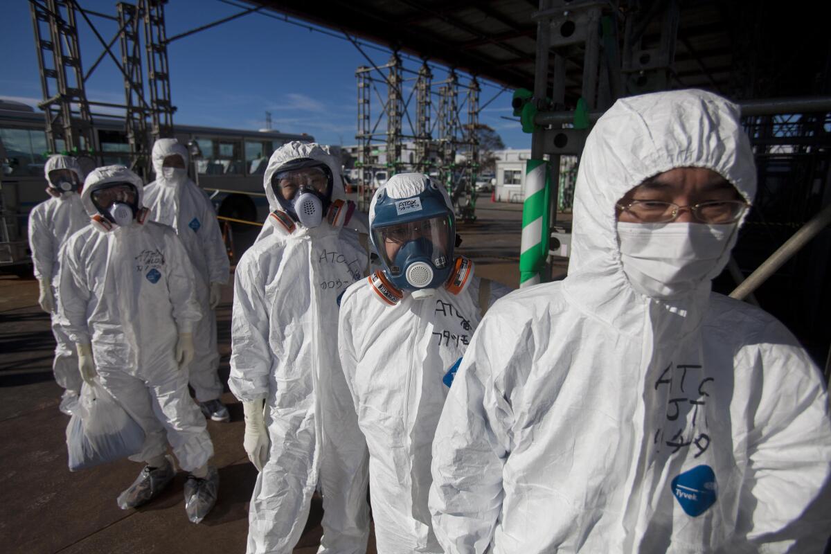 Workers in protective suits and masks wait to enter the emergency operation center at th Fukushima Daiichi nuclear power station in November 2011.