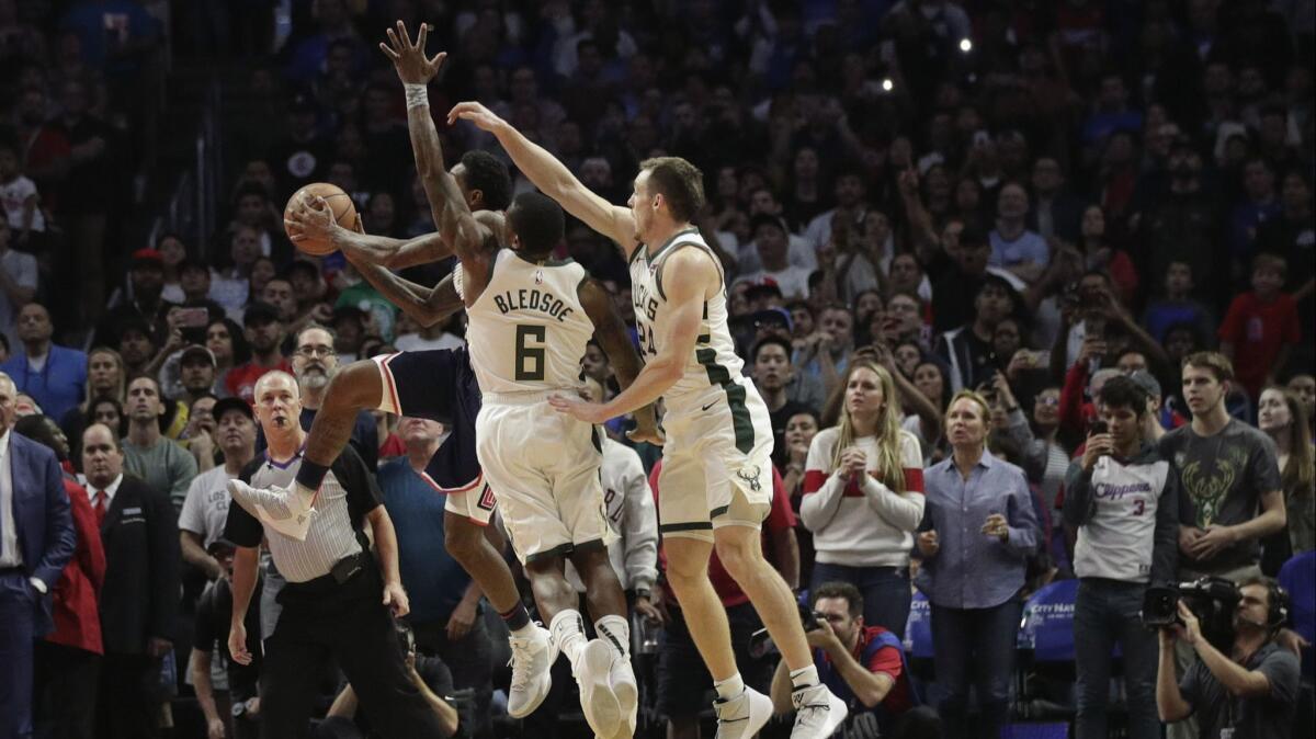 Clippers' Lou Williams puts up a shot while defended by Milwaukee Bucks' Eric Bledsoe and Pat Connaughton with less than two seconds left in overtime.