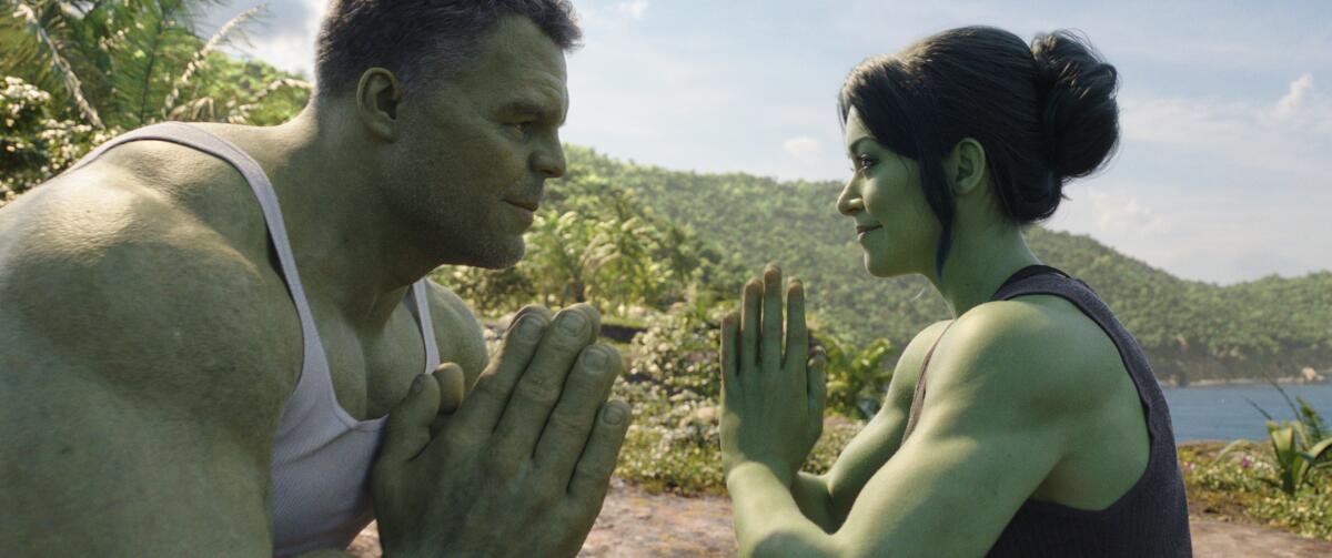 A large green man and green woman face each other while holding their palms pressed together