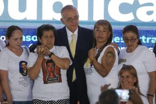 Colombia's Defense Minister Ivan Velasquez, center, stands with the relatives of 19 young people who were falsely presented as guerrillas killed in combat by the Colombian army during the country's internal conflict, during an act of recognition and public apology by the state for their extrajudicial execution, in Bogota, Colombia, Tuesday, Oct. 3, 2023. (AP Photo/Fernando Vergara)