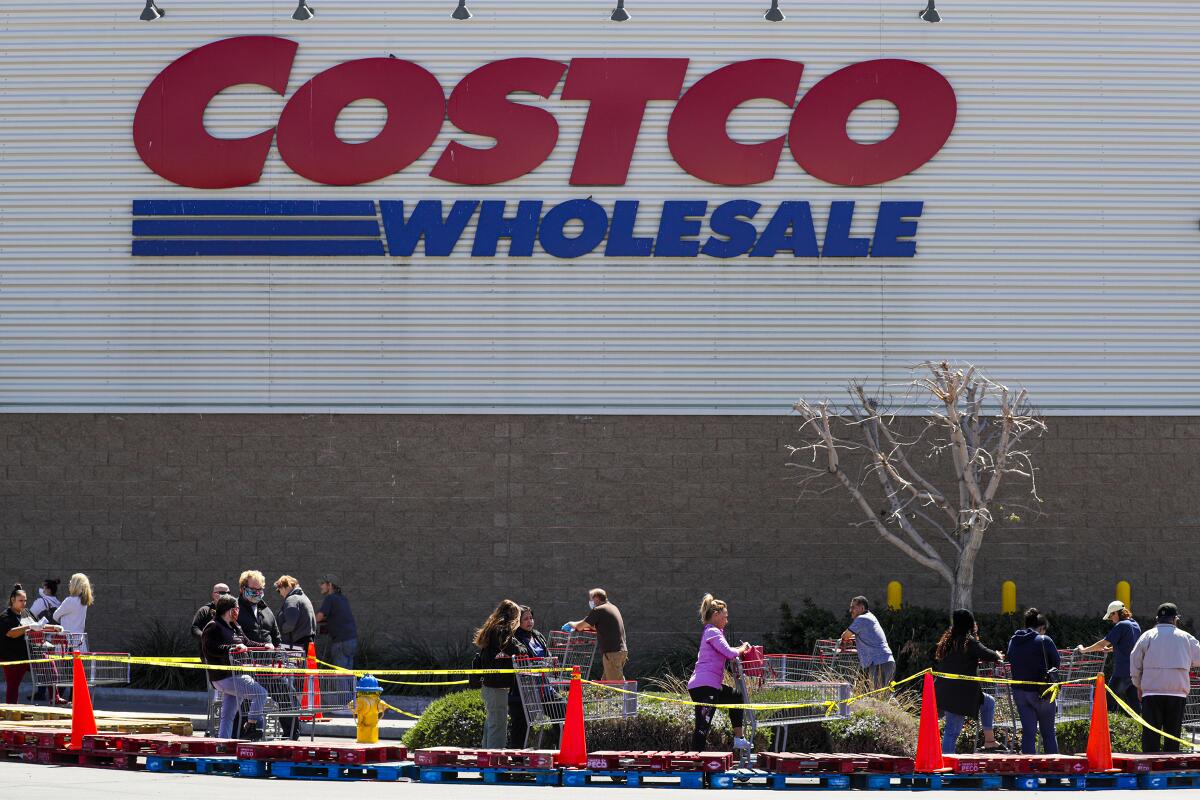 Shoppers line up Thursday outside a Costco in Victorville.