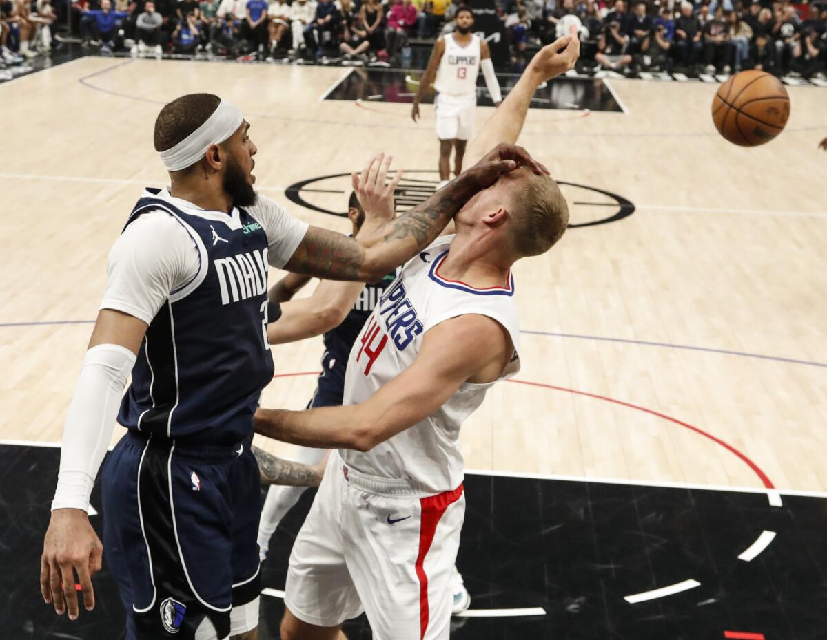 Dallas forward P.J. Washington whacks Clippers center Mason Plumlee in the face while battling for a rebound.