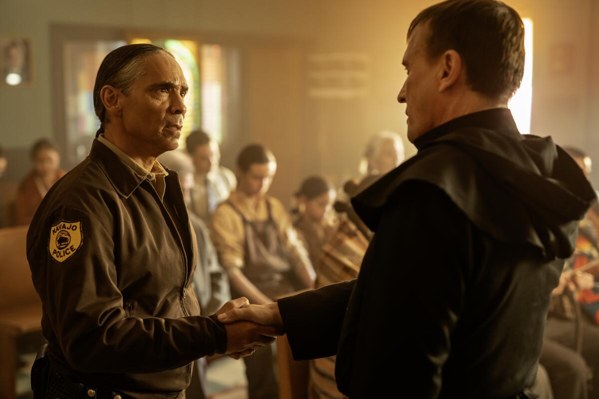 Zahn McClarnon, as Joe Leaphorn, shakes hands with a priest in "Dark Winds."