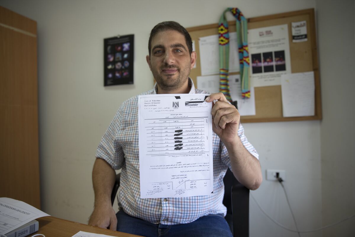 FILE - Palestinian American civil society activist Ubai Aboudi holds a copy of the Palestinian police report that includes the investigation and charges against him, at his office in the West Bank city of Ramallah, July 14, 2021. In April 2022, Israel prevented Aboudi, the director of a Palestinian civil-society group, from traveling abroad to attend a professional conference in Mexico without explanation. He is the head of Bisan, one of six Palestinian groups that Israel last year designated a terrorist organization. (AP Photo/Nasser Nasser, File)