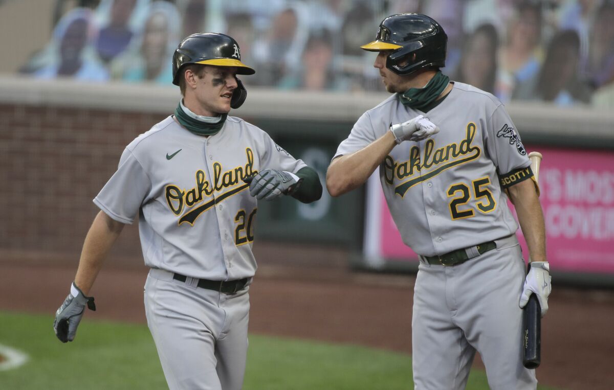 Oakland Athletics' Mark Canha, left, greets Stephen Piscotty (25) after Canha scored during the fifth inning of a baseball game against the Seattle Mariners, Monday, Aug. 3, 2020, in Seattle. (AP Photo/Ted S. Warren)
