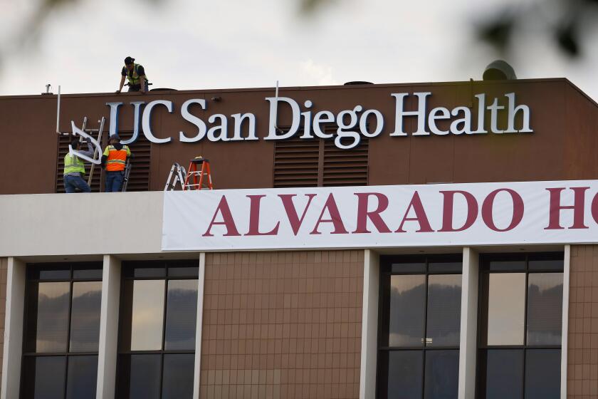 San Diego CA - December 11: Workers put up a UC San Diego Health put up a new sign on the side of Alvarado Hospital, which it took over on Monday, December 11, 2023. (K.C. Alfred / The San Diego Union-Tribune)