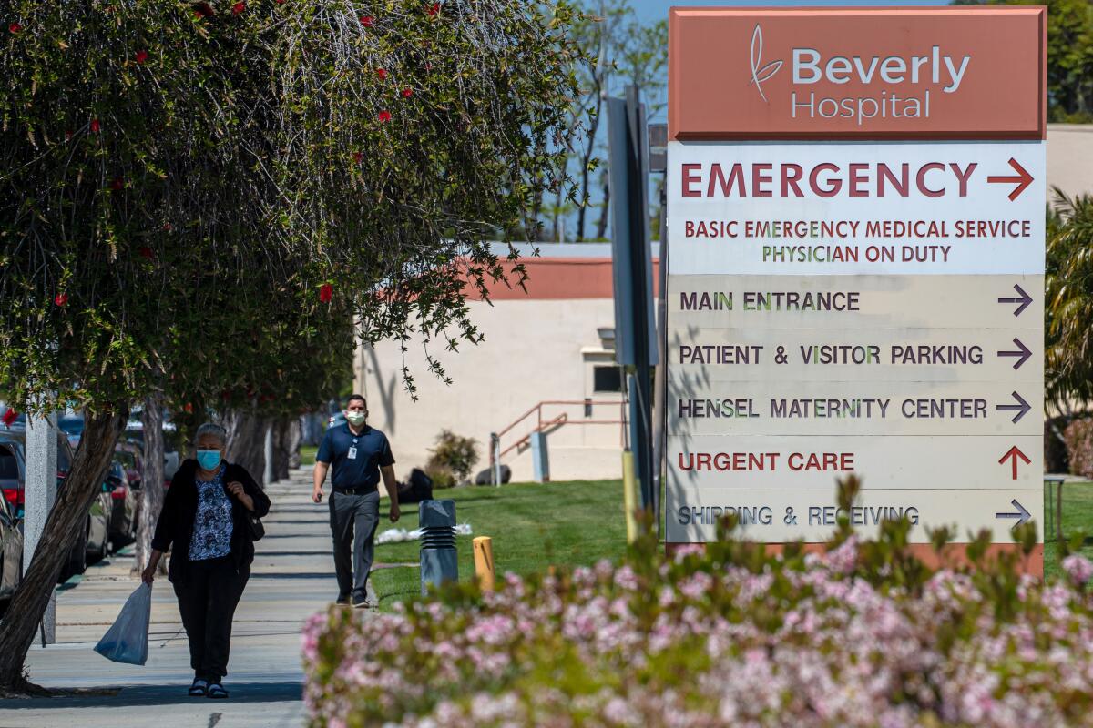 A sign in front of a hospital points with an arrow to the emergency department and other entrances.