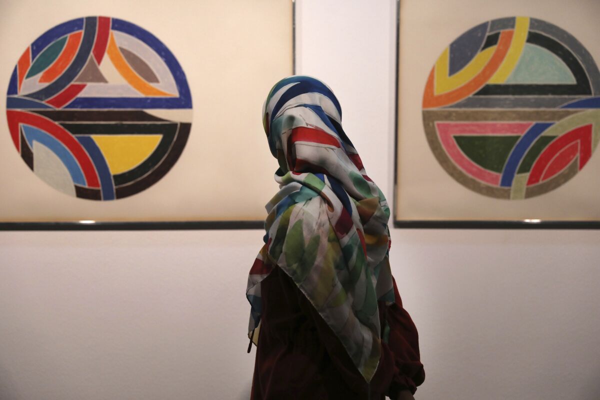 Una visitante observa la obra del pintor estadounidense Frank Stella, Sinjerli Variations No. 1-5- 1977, en una exposición de arme minimalista y conceptual estadounidense y europeo de los siglos XIX y XX, en el Museo de Arte Contemporáneo de Teherán, en Teherán, Irán, el 2 de agosto de 2022. (AP Foto/Vahid Salemi)
