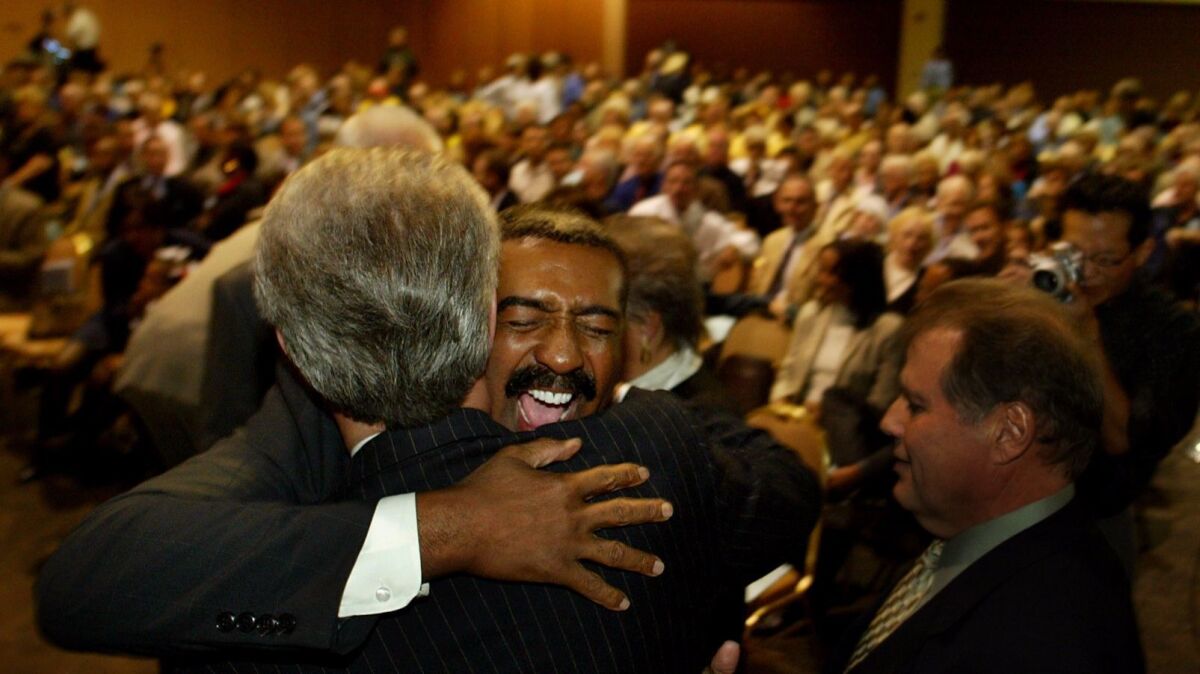 Palm Springs' first openly gay mayor, Ron Oden, hugs outgoing Mayor Will Kleindienst during his inauguration in 2003.