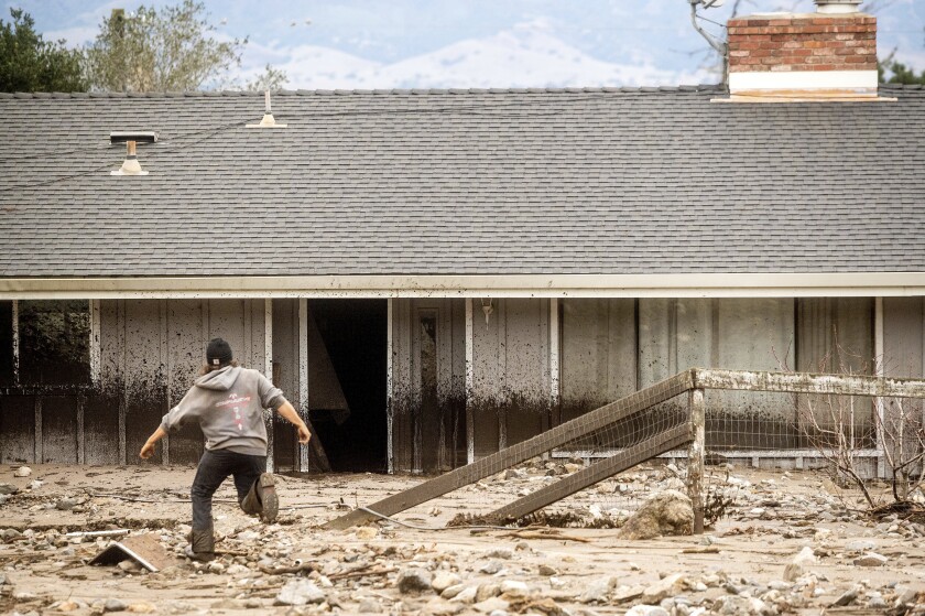 A man navigates mud while recovering belongings