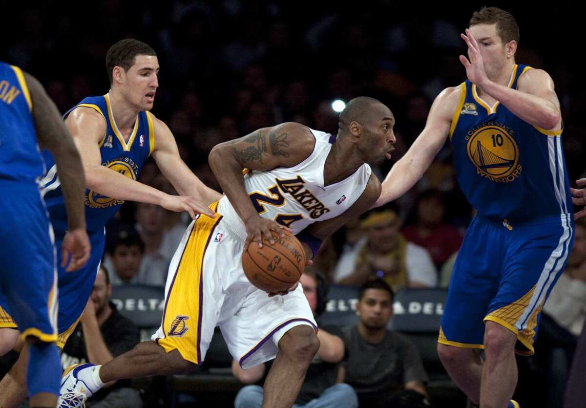 Lakers guard Kobe Bryant drives to the basket against Warriors guard Klay Thompson and forward David Lee.