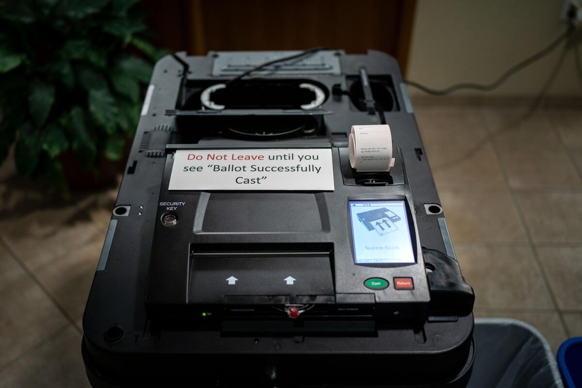 A black voting machine with a label reading "Do Not Leave until you see "Ballot Successfully Cast."
