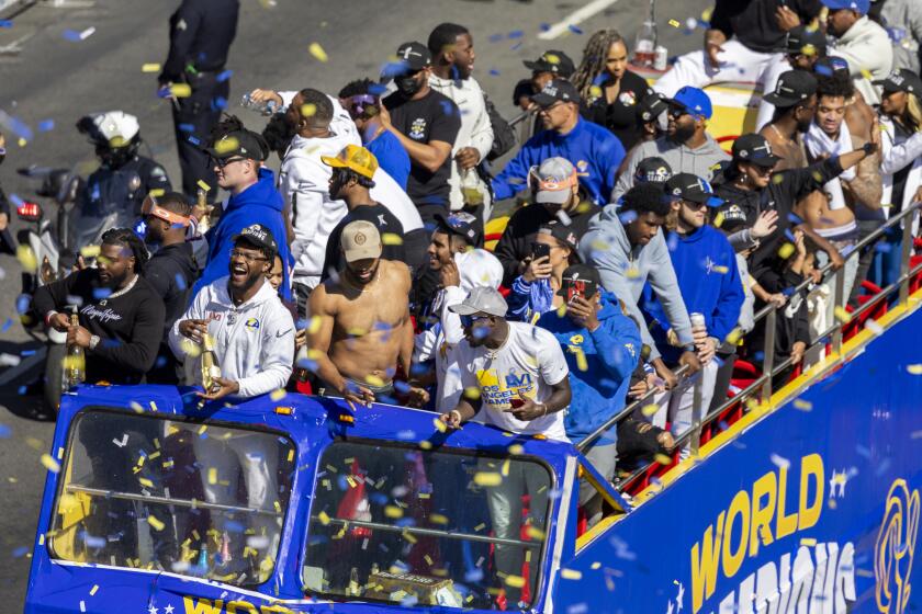 LOS ANGELES, CA - FEBRUARY 16, 2022: The Los Angeles Rams ride double-decker buses down Figueroa Street as crowds cheer during the Rams victory parade on February 16, 2022 in Los Angeles, California.(Gina Ferazzi / Los Angeles Times)