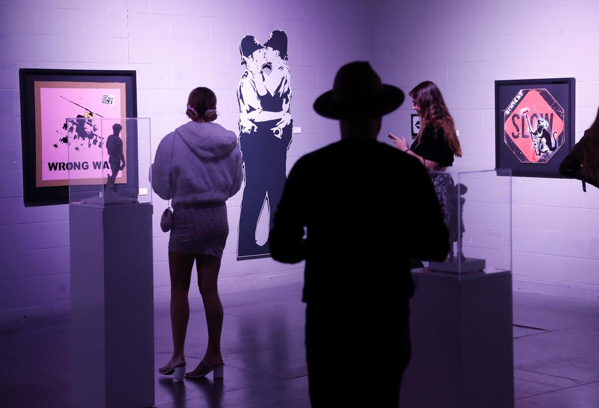 Guests admire works on the wall at the "Banksyland" exhibit.