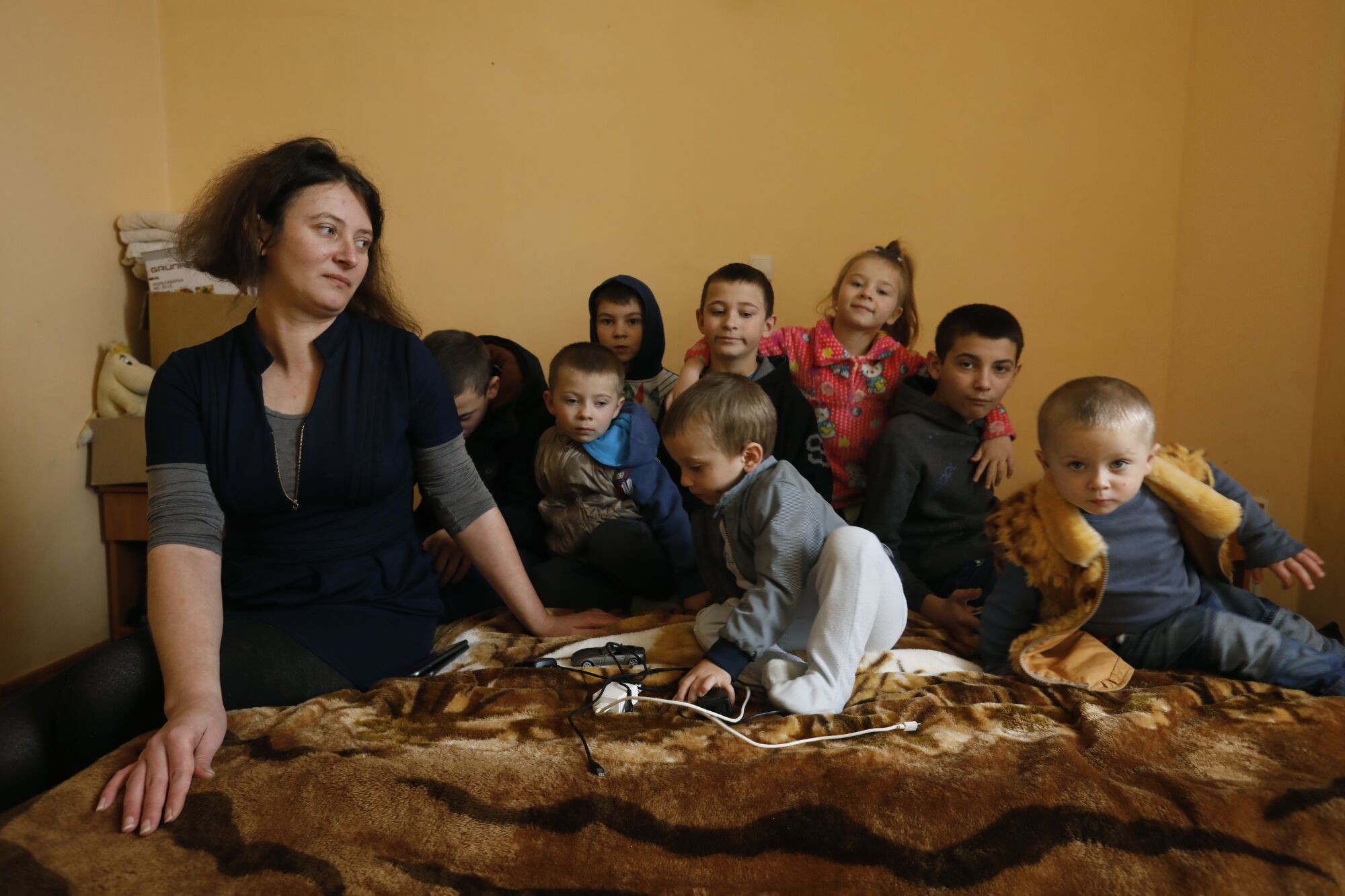 Mother with her eight children sitting on a bed in a room.