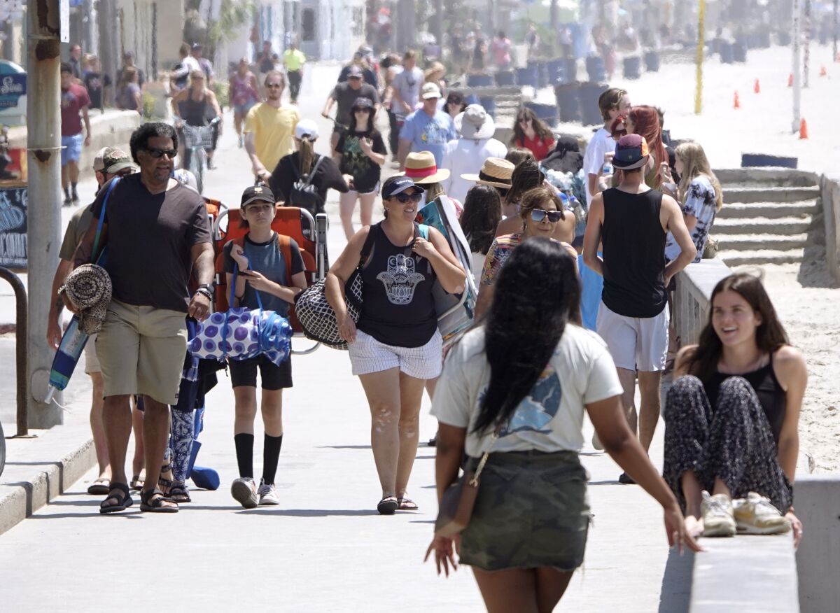 People walk along the boardwalk in Pacific Beach on Thursday. 