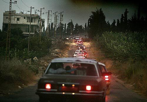 A convoy of refugees head North to Tyre along a deserted road as darkness falls in Lebanon.