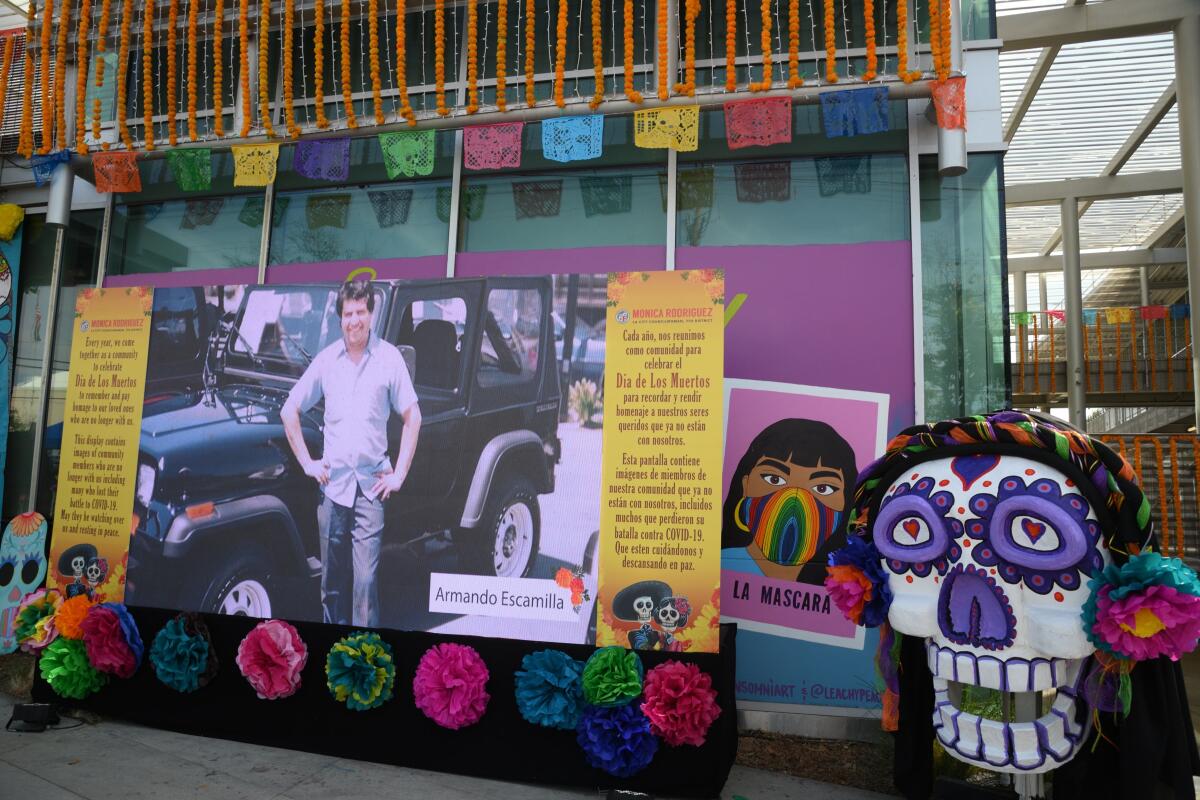 An electric ofrenda that has a photo of a man standing by a jeep and a large paper skull outside of Pacoima City Hall.