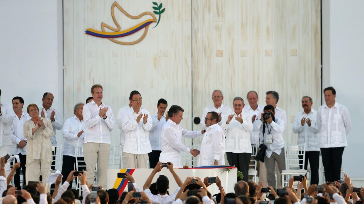 Colombian President Juan Manuel Santos, left, shakes hands with Rodrigo Londono, leader of the Revolutionary Armed Forces of Colombia, after they signed a peace agreement ending more than 50 years of conflict.