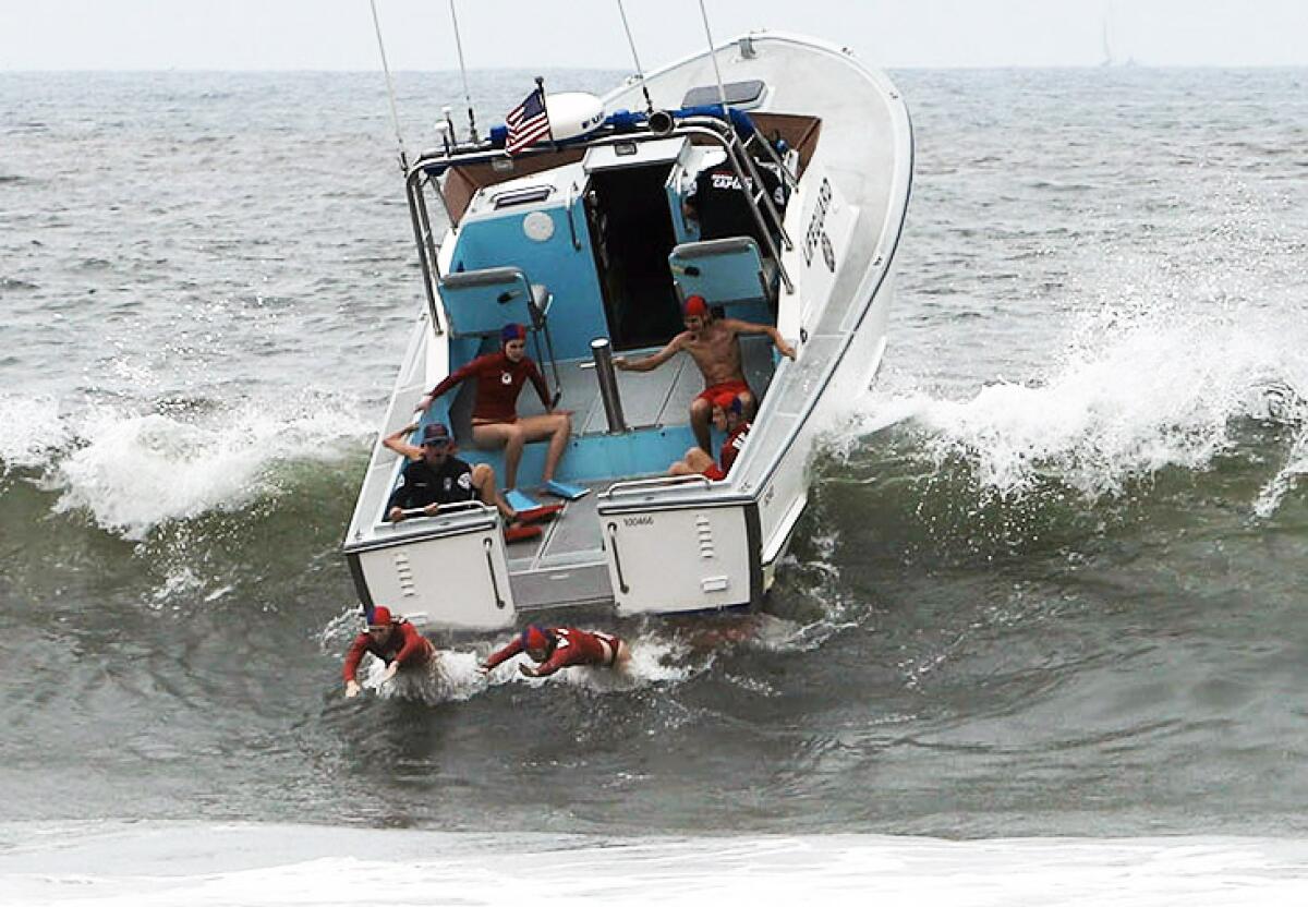 Lifeguards jump off the rescue water craft, practicing a rescue in Huntington Beach on Thursday.