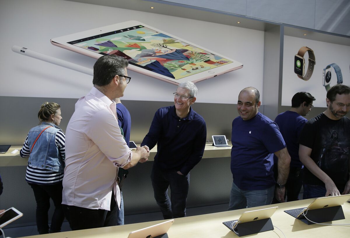 Apple Chief Executive Tim Cook shakes hands with customers during a recent visit to the Apple store in Palo Alto.