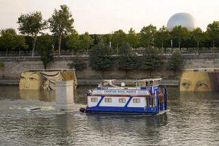 A boat sails past reproductions of artworks decorating the banks of the Seine River in Paris Tuesday