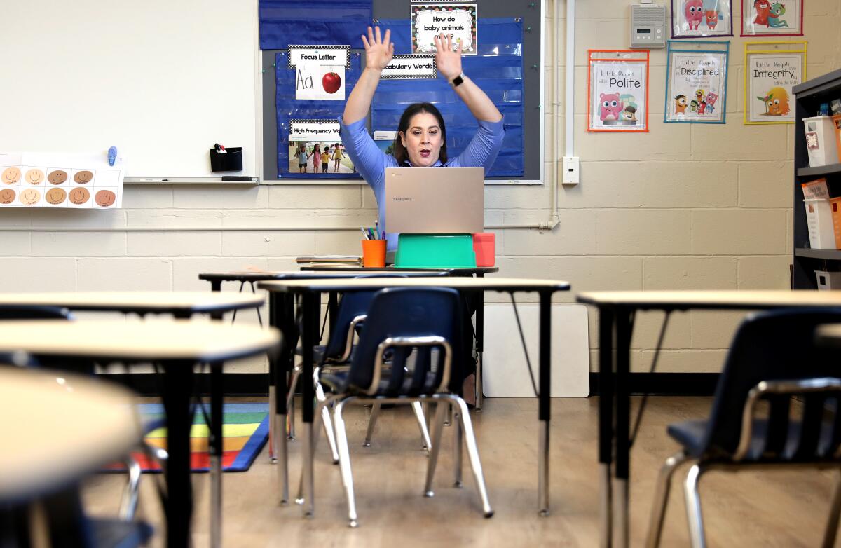 A teacher raising her arms in an empty classroom