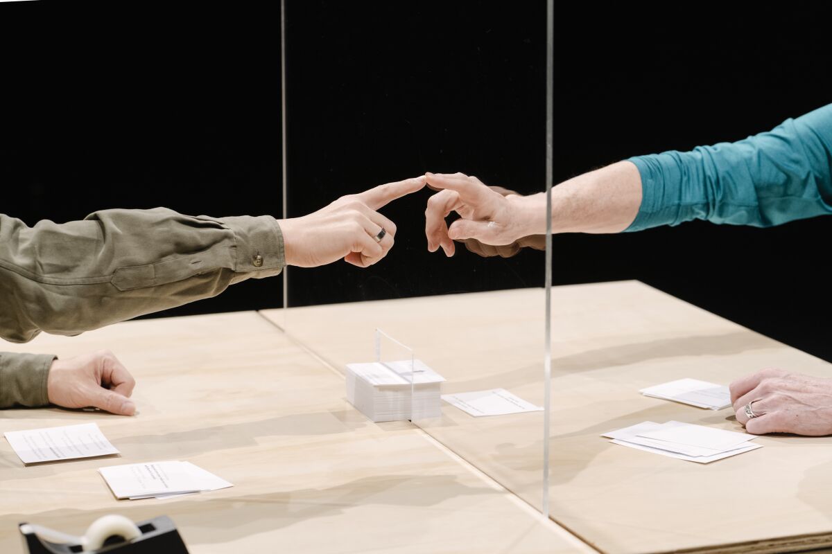 People touch fingers to the plexiglass separating them as part of "An Encounter." 