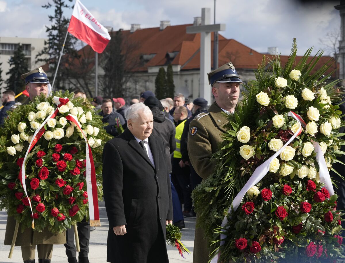 Poland's deputy prime minister and key politician, Jarosław Kaczynski,center, pays respect to his twin, the late President Lech Kaczynski, on the 12th anniversary of a plane crash in Russia that killed the president and 95 other prominent Poles, at the monument to the victims in Warsaw, Poland, on Sunday, April 10, 2022. At a time of Russia's war on Ukraine, Poland's government has revived its controversial allegations that the crash was the Kremlin's assassination plan. (AP Photo/Czarek Sokolowski)