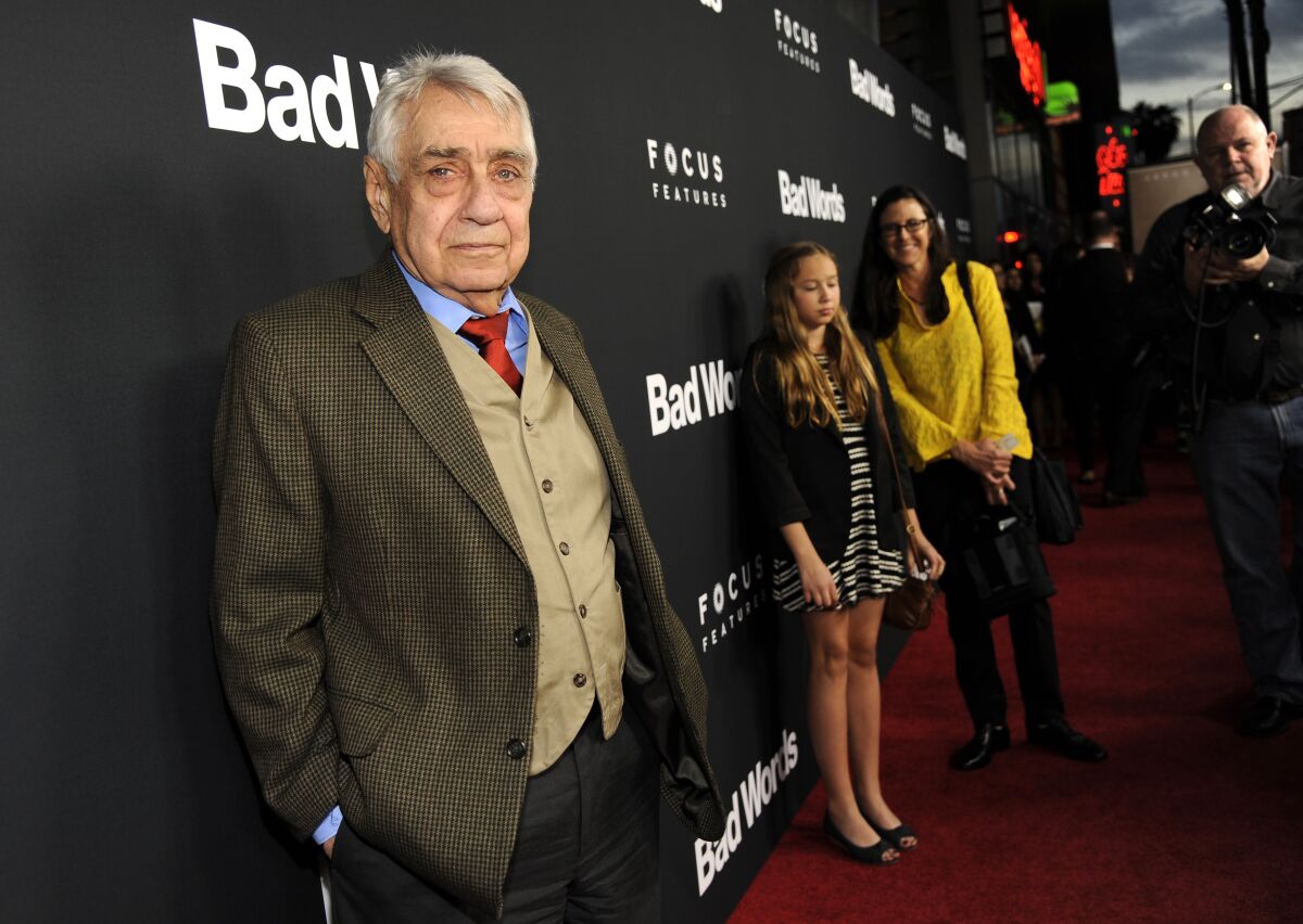 Philip Baker Hall, with a half smile, on a red carpet.