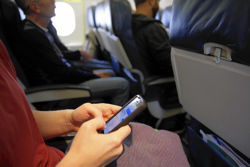 The Global Business Travel Assn., which represents about 6,000 travel managers, called the prospect of cellphone calls on planes “detrimental to business travelers.” Above, an airline passenger checks her cellphone last year.