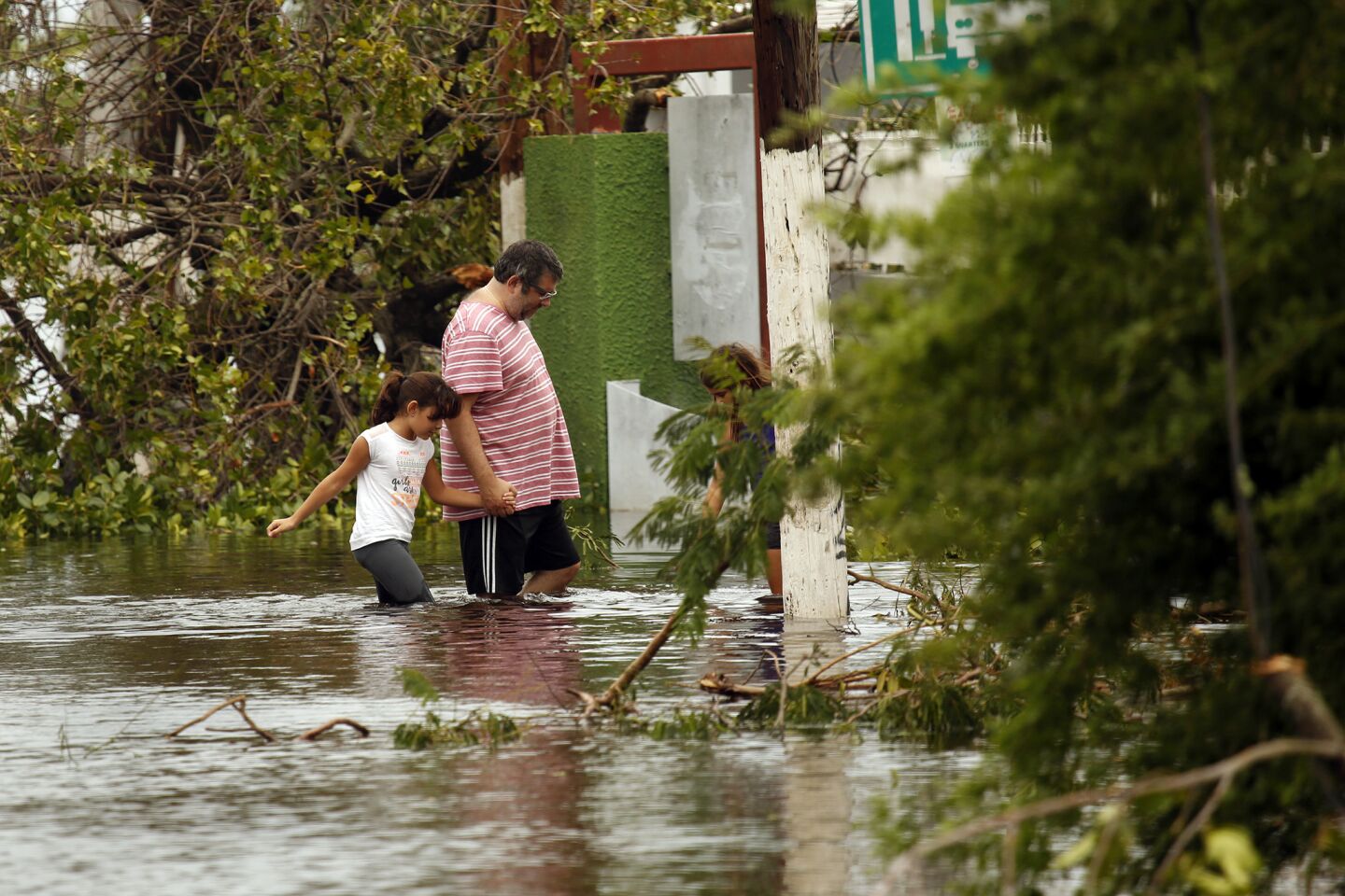 Residents of the San Juan district of Santurce wade through floodwater toward their home.
