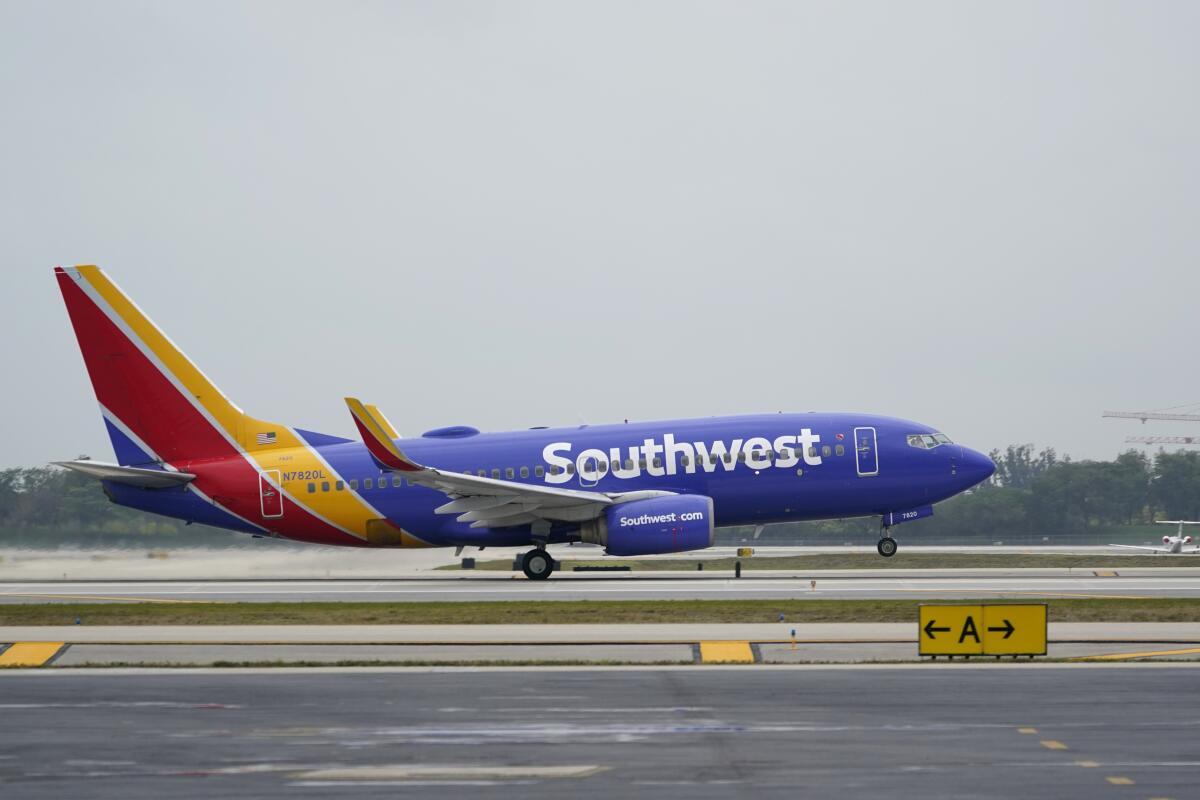 An airplane with the word "Southwest" on it takes off from a runway.