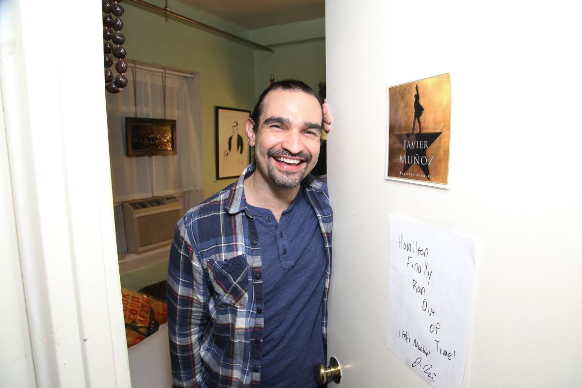 "Hamilton" star Javier Muñoz smiles while holding open a door at Richard Rodgers Theatre in New York in 2016
