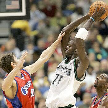 Minnesota Timberwolves forward Kevin Garnett keeps the ball out of reach of Clipper guards Marko Jaric and Quinton Ross.
