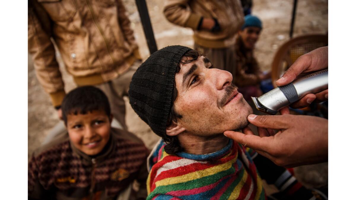 A man who identified himself as Anas gets his beard trimmed at the United Nations camp in Hamam Alil.