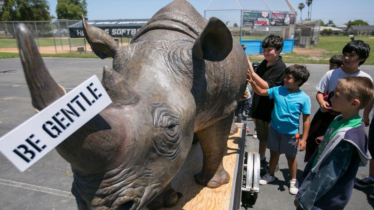 Students from Circle View Elementary School touch a life-sized rhinoceros replica during an assembly at the school on Tuesday.