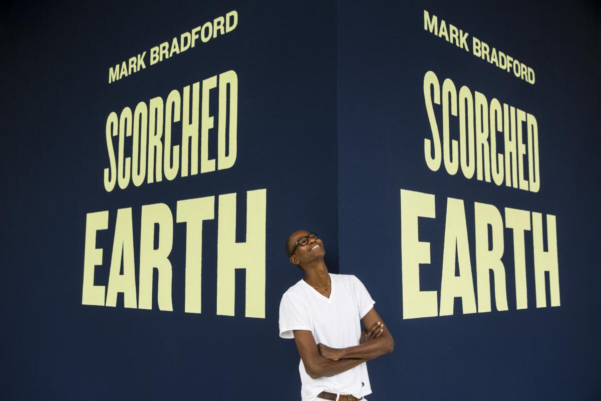 Mark Bradford in front of a sign for his solo show, "Scorched Earth," at the Hammer Museum in the summer of 2015.