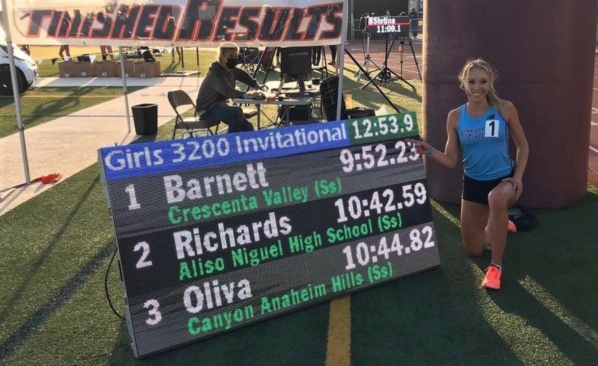 Mia Barnett kneels beside a results board during the Laguna Beach Distance Carnival on April 17.