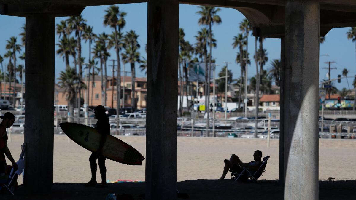 Beachgoers relax under the Huntington Beach pier in October. Officials say a record has been reached after 73 people reported stingray injuries on Friday.