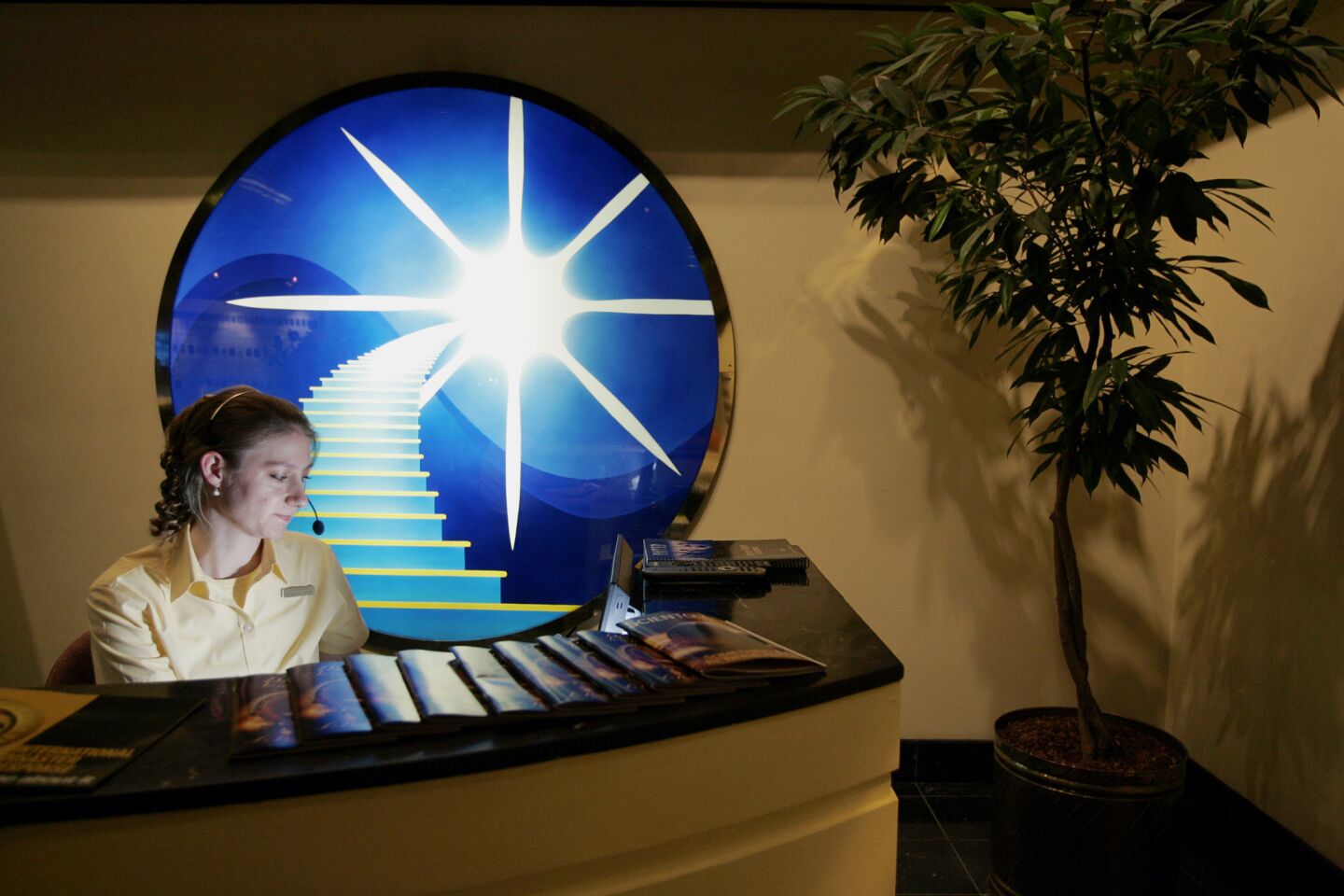 Receptionist Charlotte Heldt at Golden Era Productions. The artwork behind her depicts Scientologys Bridge to Total Freedom, the church's path to enlightenment.