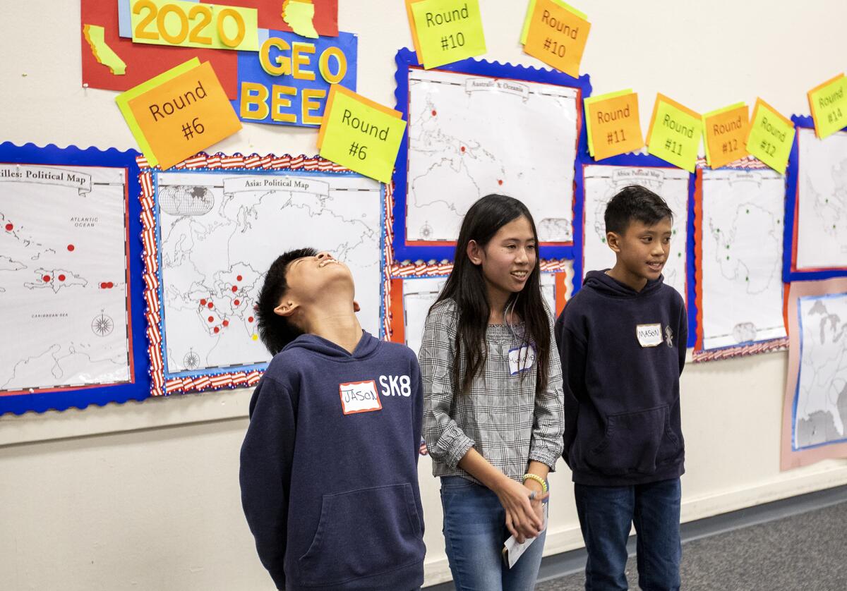 Jason Zhang, left, Michelle Nguyen and Mason Nguyen, the first-, second- and third-place finishers in Lincoln Elementary School's geography bee, react to cheers from parents and staff on Wednesday.